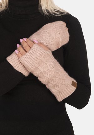 Mains avec des ongles manucurés en rose portant des gants sans doigts tricotés rose clair sur un pull à manches longues noir.