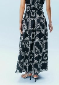 Musthave mustrõngastega must maxi kleit valgete lillede mustriga, elastse vöökohaga ja küljetaskutega. Kandmiseks metallik kõrgete kontsadega sandaalid. Pehme, kerge kangas.