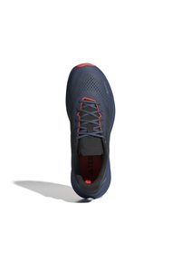 Scarpa sportiva blu e grigia con una parte superiore texturizzata, accenti rossi e lacci grigi. Presenta una suola robusta e un design in mesh traspirante.