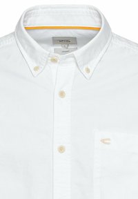 Witte button-up shirt van biologisch katoen. Heeft een klassieke kraag, beige knopen en een kleine geborduurde accent op de zak.