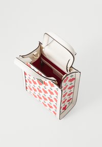 Červená a biela vzorovaná kabelka s pevnou štruktúrou, kožený materiál, zlaté kovanie a kontrastný červený interiér. Otvorený horný dizajn.