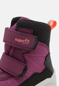 Lila und schwarze High-Top-Sneaker mit orangefarbenen Nähten und zwei Klettverschlüssen, einer mit der Aufschrift "superfit", und einer orangefarbenen Zuglasche an der Ferse.