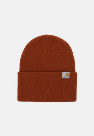 Brun strikket beanie med opslået kant og lille hvid label med Carhartt-logoet på frontens højre side.