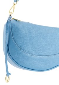 Helle blaue Lederhandtasche mit geschwungener Form, strukturiertem Oberflächen und goldenen Beschlägen. Verfügt über einen Reißverschluss und einen abnehmbaren Gurt.