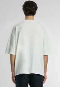 Hvit oversized t-skjorte med korte ermer, rund hals og en glatt bomullstekstur, med en rett nederkant og avslappet passform.