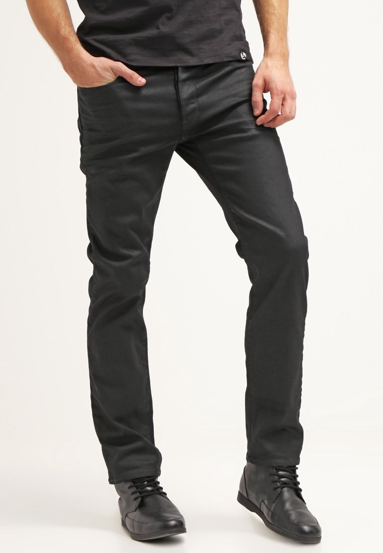 Pantalones negros de algodón con un diseño ajustado, que cuentan con bolsillos delanteros y una textura suave. Combinados con zapatillas negras.