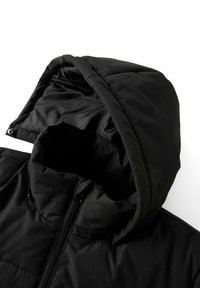 Chaqueta acolchada negra con capucha, que cuenta con cierre de cremallera y textura acolchada. El material es suave con un acabado mate; líneas limpias.