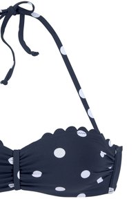 Top de bikini azul marino con lunares blancos, bordes ondulados y finas tiras ajustables. La tela parece suave con un ligero detalle de recogido.