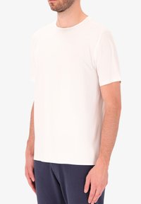 T-shirt a maniche corte, con collo rotondo, realizzato in tessuto bianco liscia. Presenta una vestibilità comoda e un design semplice senza loghi o motivi visibili.