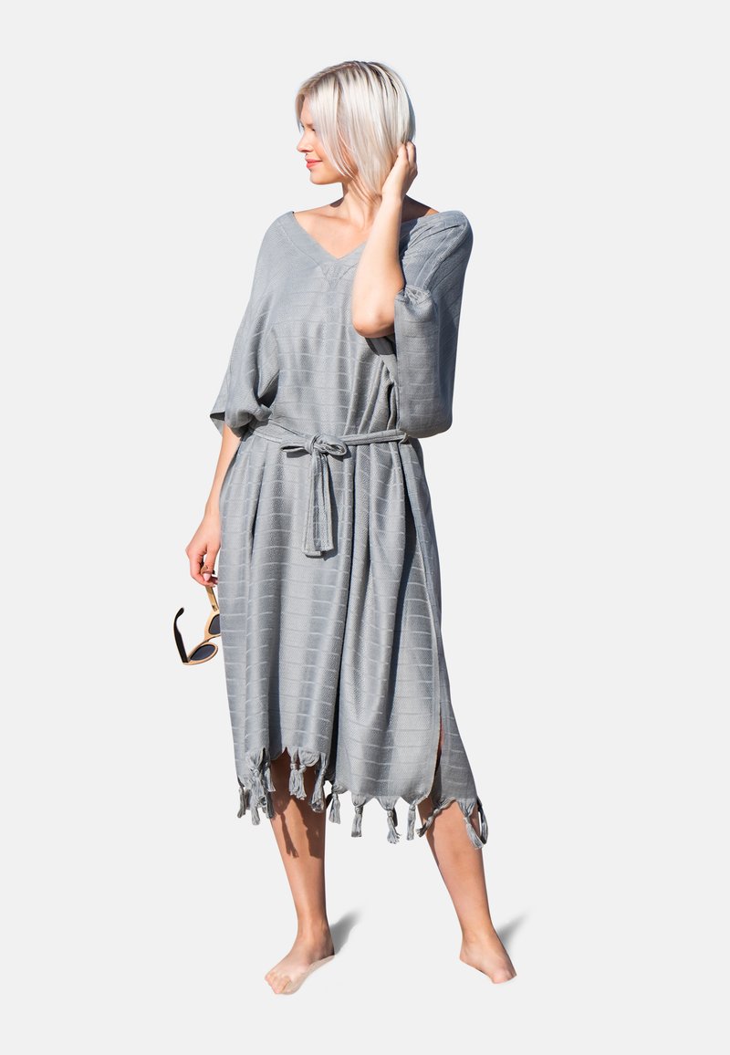 Vestido de lino gris con corte holgado, escote en V y mangas anchas. Presenta una cintura anudada y un dobladillo con flecos, con un patrón de cuadrícula texturizado en toda la prenda.