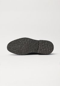 Zwarte rubberen schoenzool met een gestructureerd, gemarmerd oppervlak, voorzien van een ronde neus en een lichte hak. Duurzaam en flexibel ontwerp.