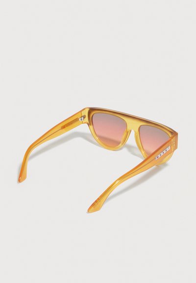 Yellow translucent plastic sunglasses with pink-tinted lenses, wide arms, and a white label with red text on the right temple.
