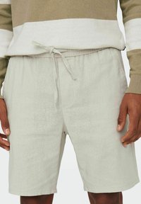 Pantaloni scurți din in gri deschis, cu talie elastică și șnur. Include buzunare laterale și o croială lejeră pentru confort.