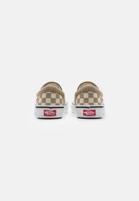 Béžové kostkové slip-on tenisky Vans s bílými podrážkami. Vybavené polstrovaným okrajem a červeným logem na patě. Hladký textilní materiál.