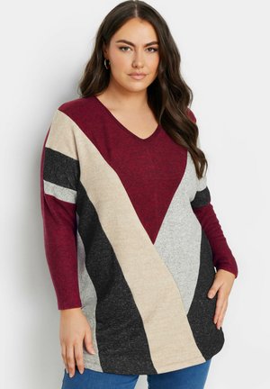 Maglione colorato in blocchi di rosso, grigio, nero e crema, con scollatura a V e maniche lunghe. Tessuto morbido, vestibilità rilassata e design geometrico asimmetrico.