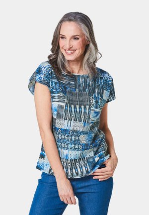 Korte mouwen blauwe top met print in verschillende patronen en texturen, gemaakt van lichte stof. Gecombineerd met blauwe jeans.