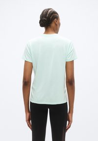 Αθλητική κοντομάνικη μπλούζα σε ανοιχτό μέντα πράσινο χρώμα, με στρογγυλή λαιμόκοψη και λεία υφή, που φέρει ένα διακριτικό λογότυπο στο πίσω μέρος.