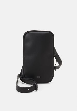 Sort lille rektangulært crossbody-taske med lynlås, justerbar rem og "ZIGN"-logo foran.