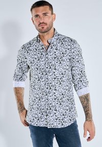 Weißes Hemd mit Knopfverschluss, verziert mit einem grünen Blatt- und Blumenmuster, mit hochgekrempelten Ärmeln, schlanker Passform und weicher Textur.