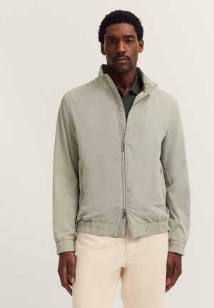 Light green, lightweight bomber jacket with a stand-up collar, front zipper, elasticized cuffs, and waistband; smooth texture, minimalist design.