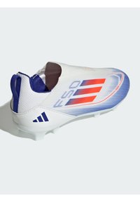 White and blue soccer cleat with a molded design, featuring orange accents and a slip-on style. Textured upper and studded sole for traction.