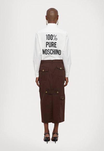 Weißes Langarmshirt mit dem Aufdruck "100% PURE MOSCHINO" auf der Rückseite. Brauner Midirock mit Cargo-Taschen und goldenen Knopf-Akzenten.