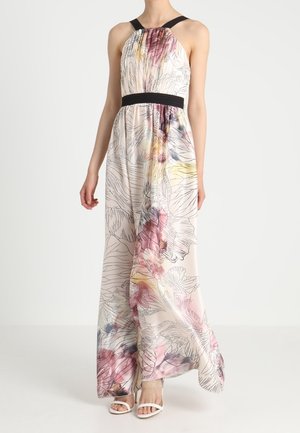 Mouwloze maxi-jurk met halterhals en zwarte tailleband, met abstracte bloemenpatronen in roze, geel en blauwe tinten. Witte open-teen hakken.