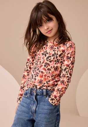 Camicia a maniche lunghe con stampa leopardata in tonalità di pesca, rosa e marrone. Abbinata a jeans di denim blu con un classico design a vita alta.