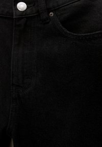Gros plan sur un jean en denim noir montrant la poche avant, la boucle de ceinture, le bouton et les détails des rivets.