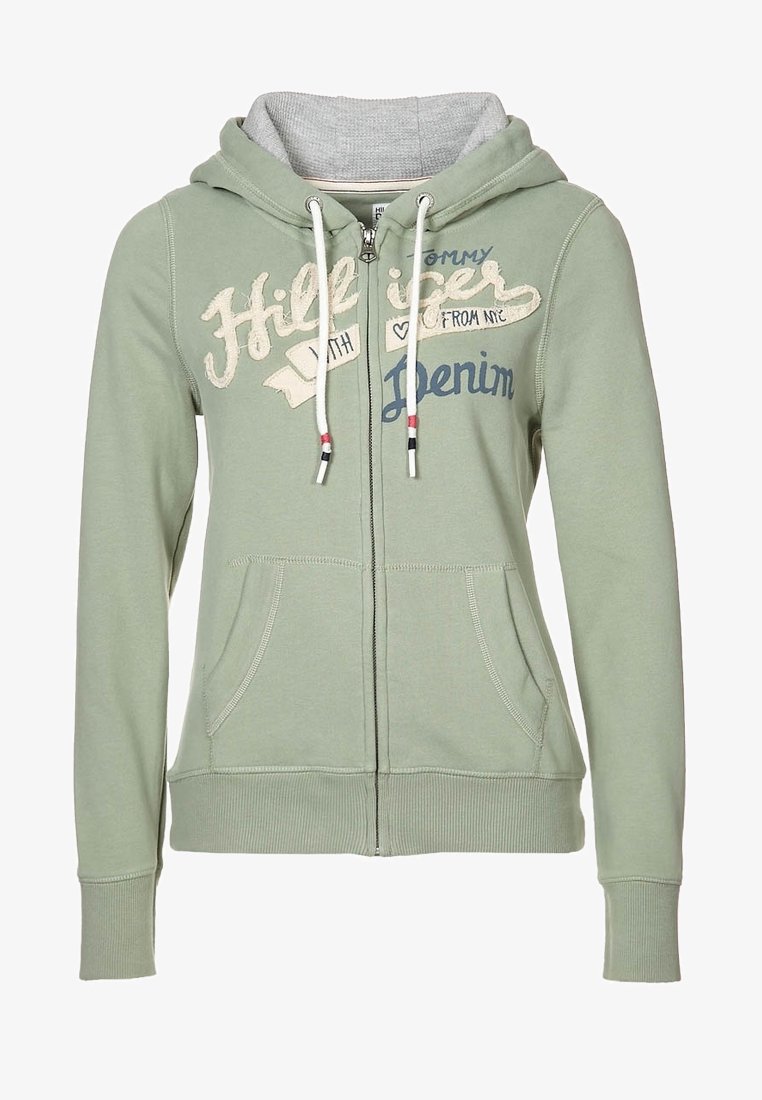 Zelená mikina s kapucí na zip z měkké tkaniny, s šedým vnitřkem, předními kapsami a vytištěným textem v krémové a námořnické modři. Ozdobená stahovacími šňůrkami.