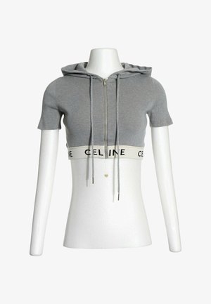 Grauer kurzärmeliger, kurz geschnittener Hoodie mit Frontreißverschluss, Kordeln und weißem elastischem Saum mit schwarzem "CELINE"-Text auf einer weißen Schaufensterpuppe.