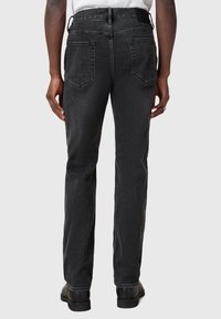 Mustat farkut suoranlahkeisella leikkauksella, viidellä taskulla ja ommellulla vyötäröllä. Liu'utusmainen koostumus ja haalistunut värikuvio.