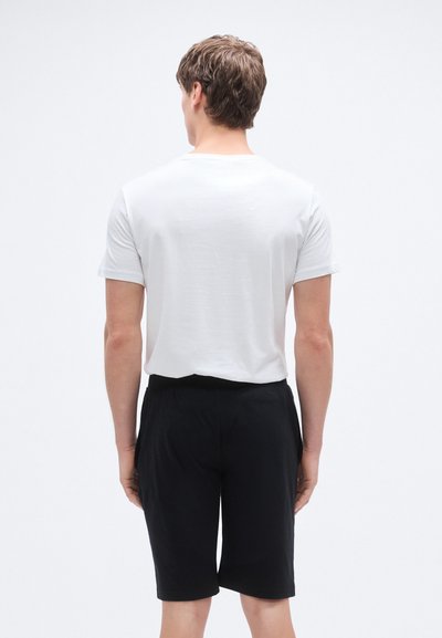 Balti trumpomis rankovėmis marškinėliai su apvalia iškirpte, derinami su juodais kelnaitėmis iki kelių. Audinys atrodo minkštas ir laisvo kirpimo.