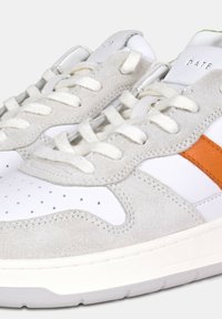 Sneaker bianca con tomaia in suede grigia, striscia laterale arancione e punta bianca testurizzata. I lacci e i dettagli di cucitura bianchi completano il design.