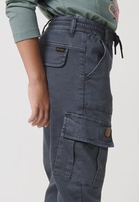 Morske cargo hlače iz mešanice bombaža, z elastičnim pasom, več žepi in kožna oznaka na strani.