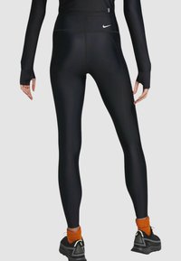 Czarne legginsy sportowe wykonane z gładkiego, elastycznego materiału. Wysoki stan z subtelnymi detalami szwów i małym logo na tylnej części pasa.