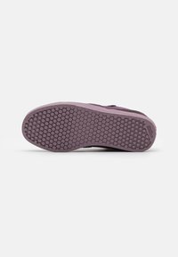 Suola di sneaker in gomma viola con un motivo a nido d'ape. Design piatto con battistrada pronunciato e marchio sul lato. Texture morbida.