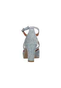 Sandalias de tacón alto de ante gris claro con correa ajustable en el tobillo, tacón abierto y diseño curvado, que cuentan con una superficie texturizada suave.
