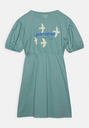 Robe en coton bleu sarcelle clair avec manches courtes bouffantes, taille froncée et un imprimé graphique d'oiseaux avec le texte « SANTORINI BIRD'S EYE VIEW ».
