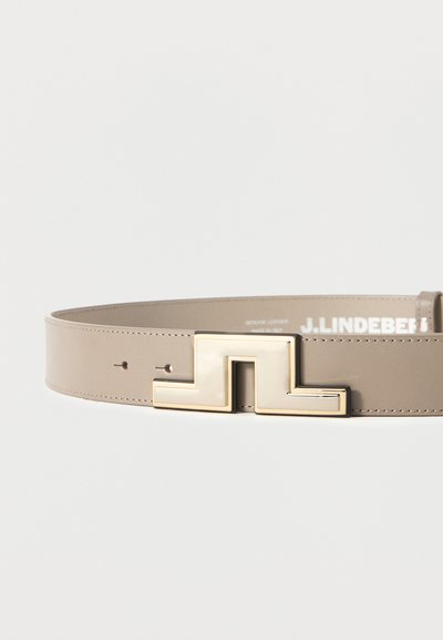 Μπεζ δερμάτινη ζώνη με χρυσή γεωμετρική μεταλλική αγκράφα, που διαθέτει δύο μικρές τρύπες ρύθμισης και εμφανές το όνομα της μάρκας στο εσωτερικό.