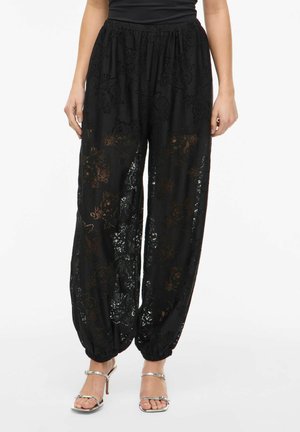 Černé krajkové kalhoty s květinovým vzorem, s elastickým pasem a nařasenými lemy. Lehká tkanina s poloprůsvitnou texturou.