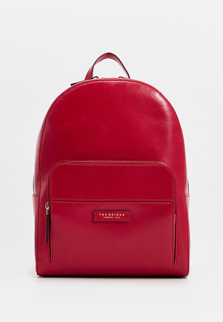 Roter Leder-Rucksack mit runder Form, vorderer Reißverschlusstasche und einem Logopatch. Glatte Textur mit genähten Details.