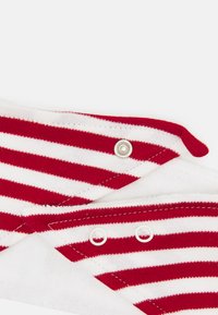 Tecido listrado em vermelho e branco com textura suave, apresentando fechos de pressão e um design de borda dobrada, adequado para vestuário casual.