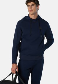 Sudadera navy con capucha, cordones ajustables y mangas raglán. Hecha de una tela suave, cuenta con una cintura y puños ajustados.