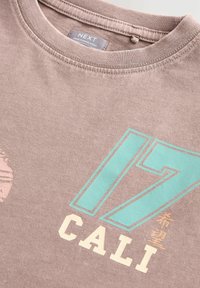 Hnědé bavlněné tričko s kulatým výstřihem, s tyrkysovými grafikami "17" a "CALI", a světle růžovým kruhovým designem.