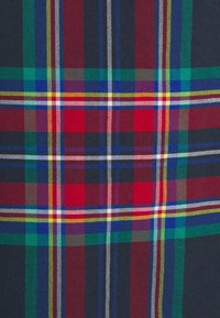 Motif tartan rouge, bleu, vert, jaune et blanc avec des bandes croisées formant des carrés sur un tissu tissé.