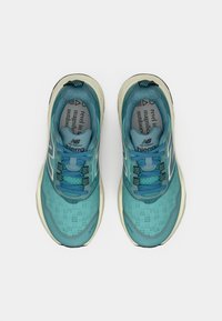 Teehelendavad jooksujalatsid hingava võrgukattega, polsterdatud tald ning kontrastsed valged detailid. Omavad siniseid paelu ja tekstuuri mustrit.