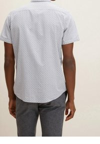 Camicia a maniche corte in tessuto azzurro chiaro, caratterizzata da un motivo a griglia con dettagli blu scuro. La vista posteriore mostra un orlo dritto e il colletto.
