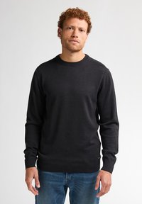 Donkergrijze trui met een ronde hals, ribbelboord aan de hals en manchet, gemaakt van een gladde stof. G gedragen met blauwe jeans, zonder zichtbare patronen.