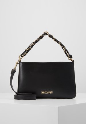 Borsa a spalla in pelle nera con catena dorata e manico intrecciato in pelle, logo dorato "Just Cavalli" sul davanti, poggiata su una superficie bianca.